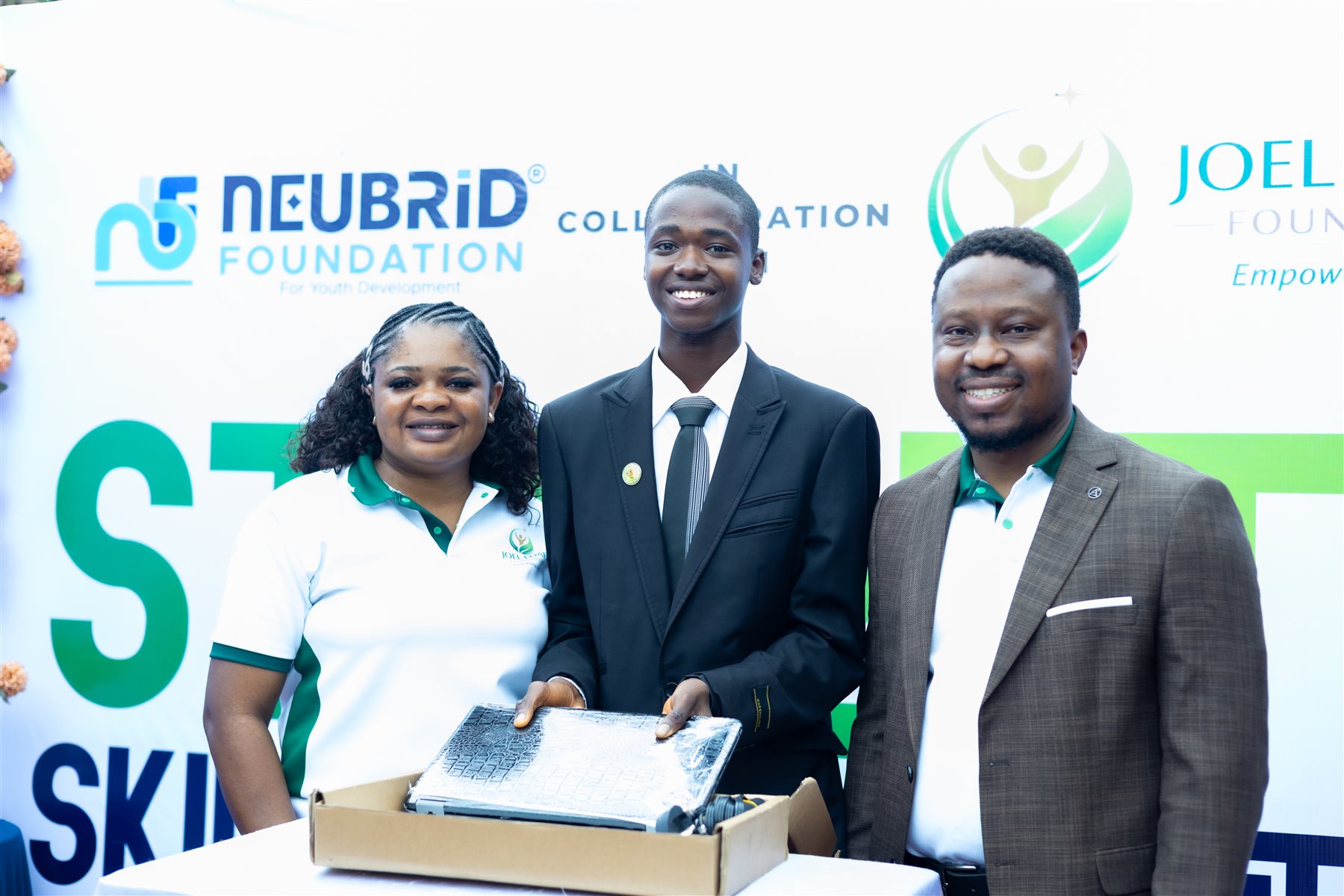 A young participant with a laptop alongside foundation representatives
